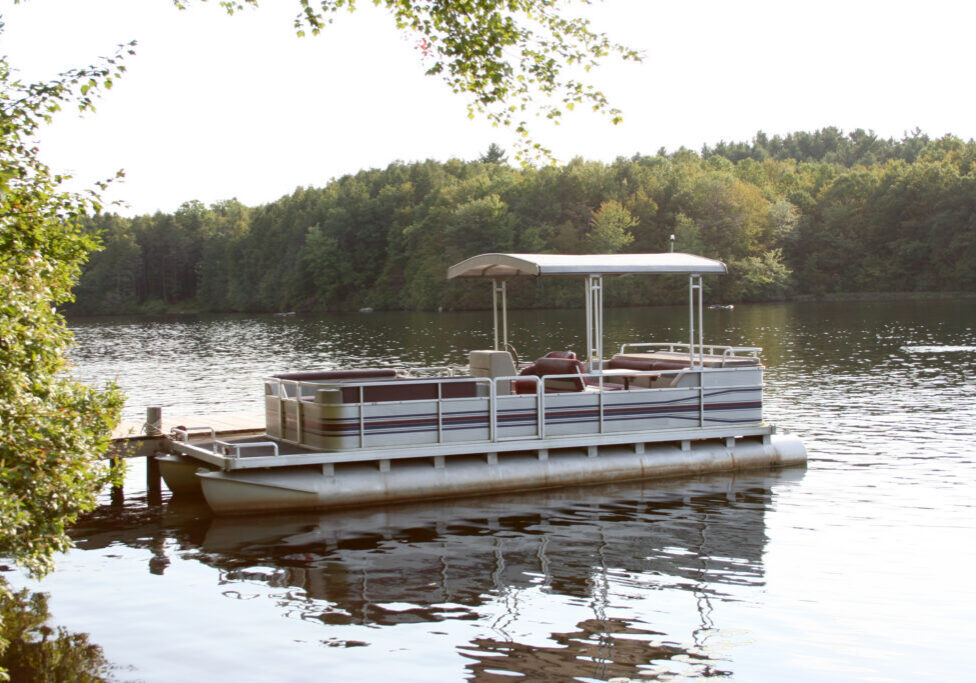 A pontoon boat moored to a dock.